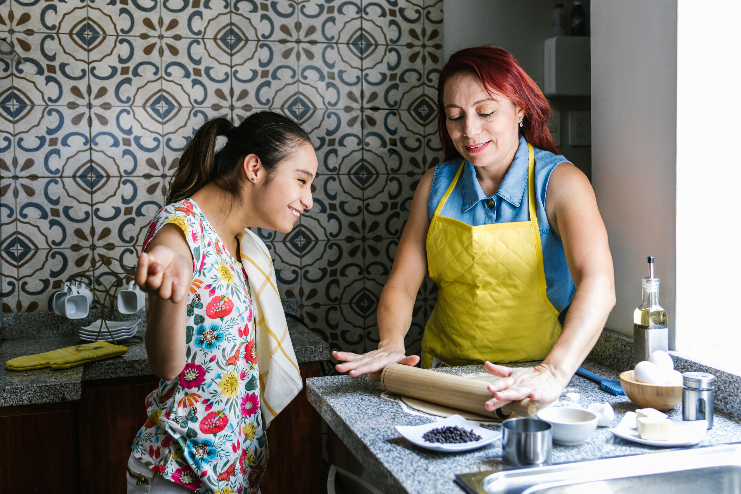 Hispanic girl with cerebral palsy and her mother cooking at home, in disability concept in Latin America