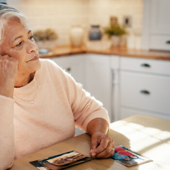 Thinking, senior woman and picture at house for mourning loss, memory past and reminder for history. Elderly person, grief and old image with loneliness, remember partner and nostalgia for retirement