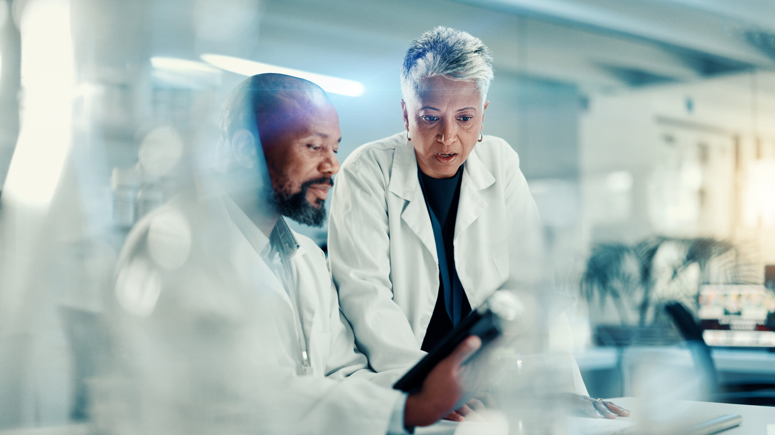 Discussion, scientists and team with tablet, lab or collaboration for medical research for analysis. Healthcare, science and mature people with tech for biotechnology, breakthrough and communication