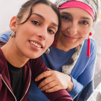 Mother and daughter smiling while taking a selfie together during lunch, showing support and love during cancer recovery