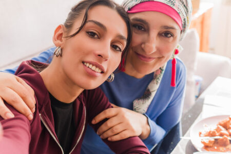 Mother and daughter smiling while taking a selfie together during lunch, showing support and love during cancer recovery