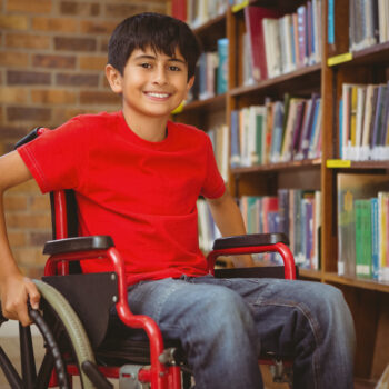 Portrait of boy sitting in wheelchair at library