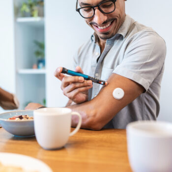 Hispanic Male Using Insulin Pen at Breakfast Table with a Smile