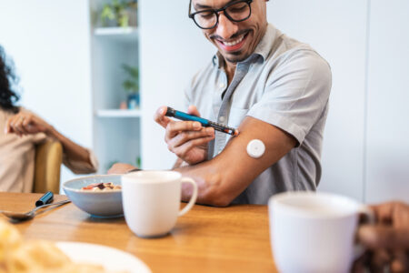 Hispanic Male Using Insulin Pen at Breakfast Table with a Smile