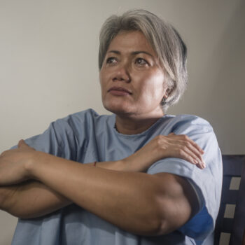 dramatic portrait of attractive sad and depressed mature woman with grey hair in pain suffering mental disorder or depression problem wearing patient gown feeling sick and abandoned