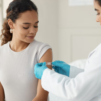 Shot of a young doctor applying a band-aid after injecting her patient during a consultation in the clinic