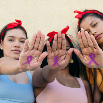 Three Women with symbol of breast cancer drawing on hand